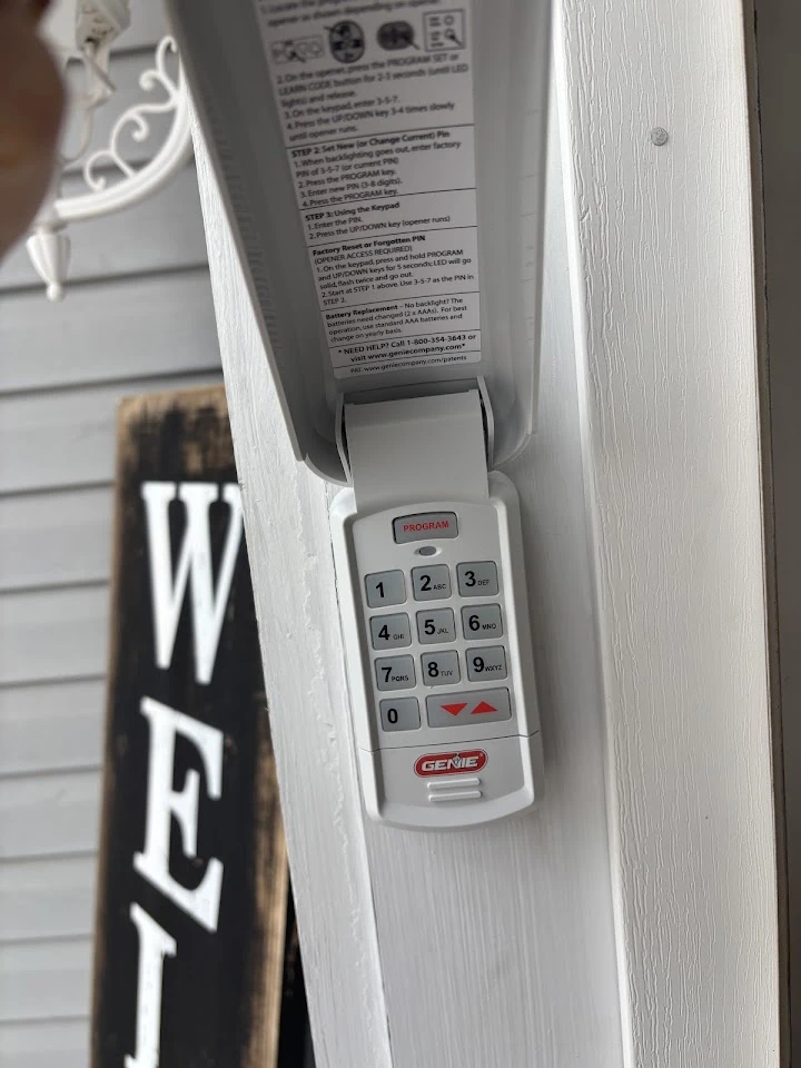 A white Genie garage door keypad on a door frame.