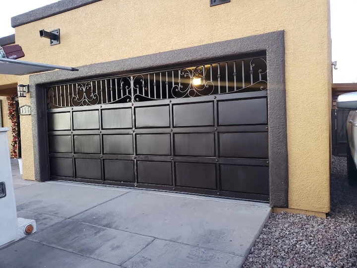 Custom dark metal garage door with decorative scrollwork.