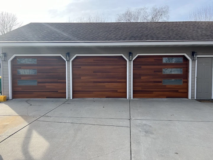 Three-car garage with wood-look doors by Scray.