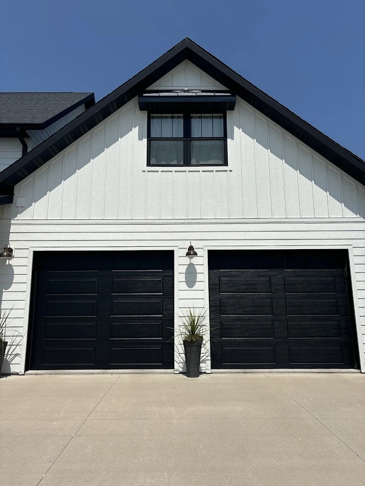 Two black garage doors on a white home.