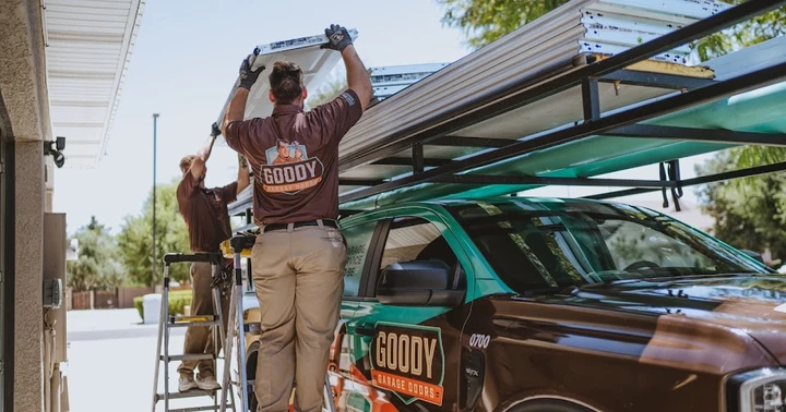 Two Goody Garage Doors workers loading parts onto a truck.
