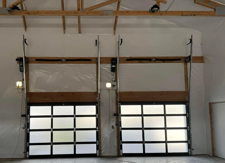 Two modern glass garage doors in a bright workshop.