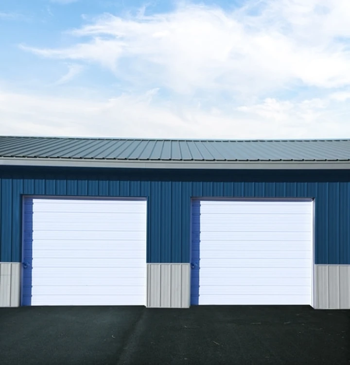 Two white garage doors on a blue storage facility.
