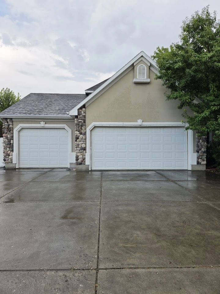 Two white garage doors with stone accents.