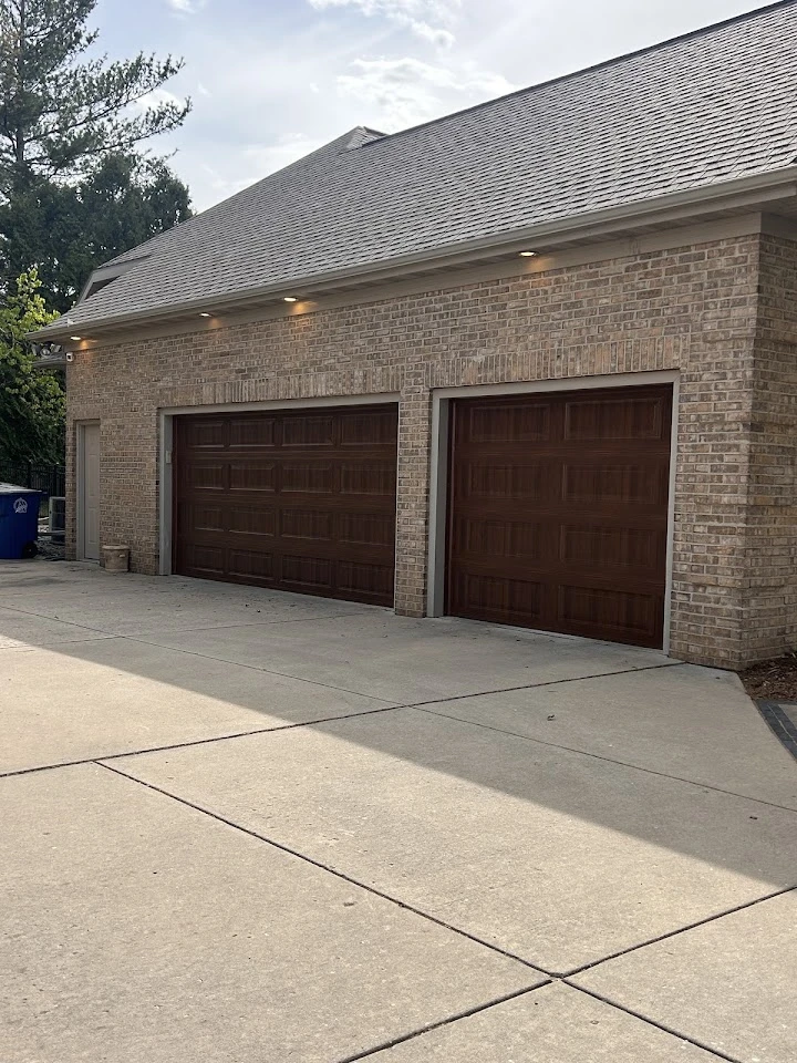 Two wooden garage doors on a brick home.