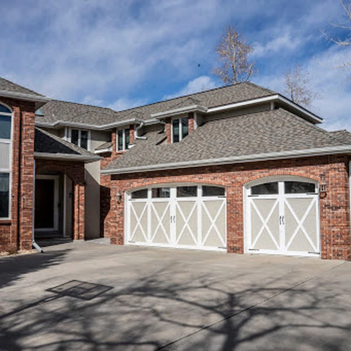 A brick house with two white carriage-style garage doors.