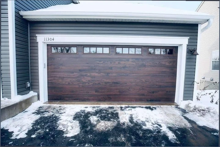 A dark wood-finish garage door with four windows.