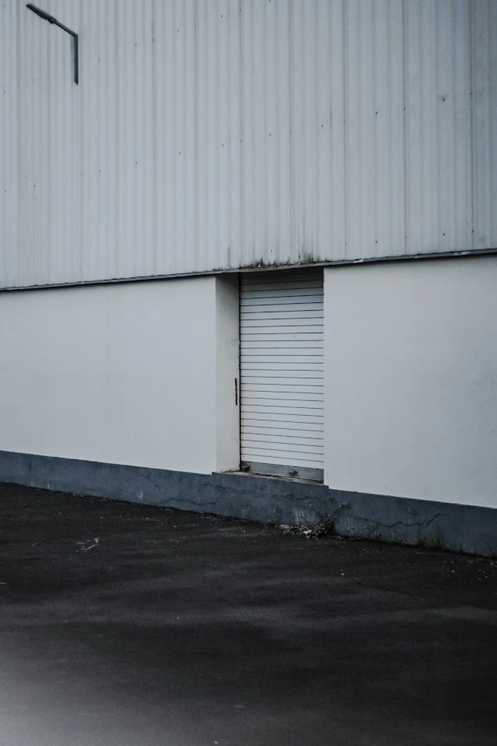 A white industrial building with a closed roll-up door.