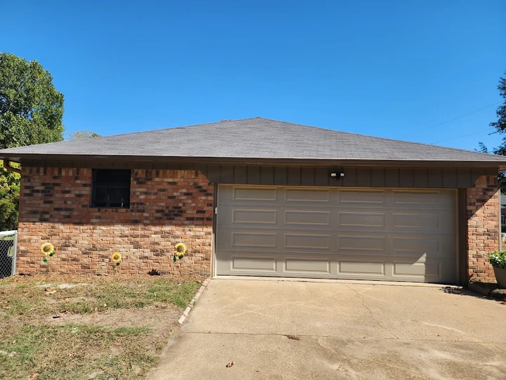 Brick garage with a tan door and sunflower decor.