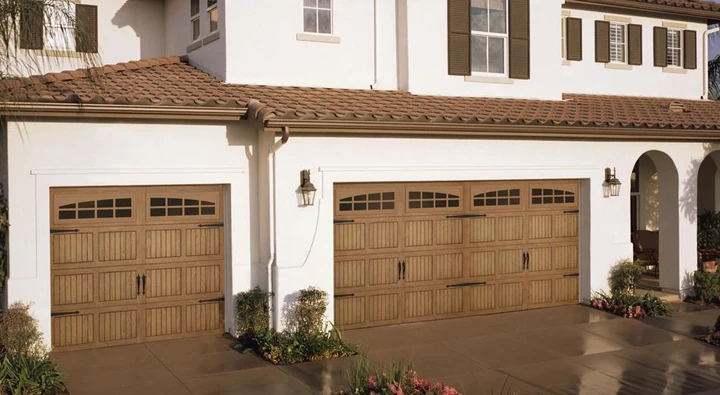 Brown wooden garage doors on a white house.