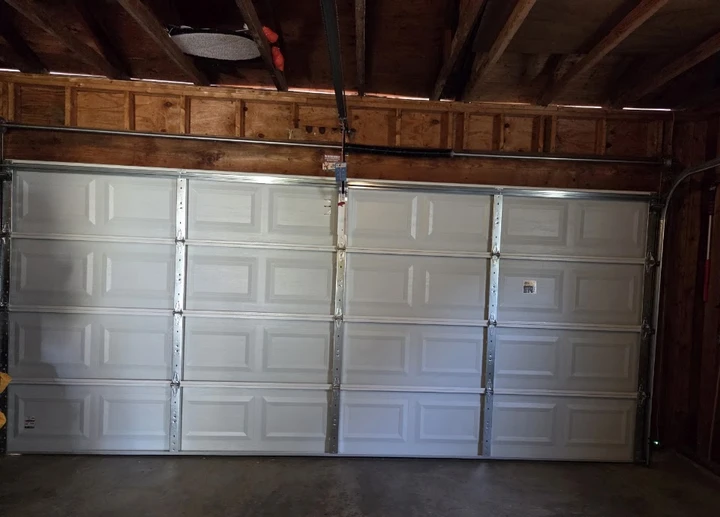 Closed white garage door inside a wooden garage.