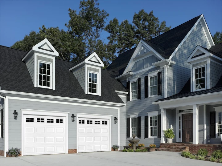 Precision garage door installation on a gray house.