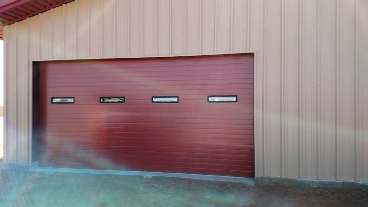 Red garage door on a beige metal building.