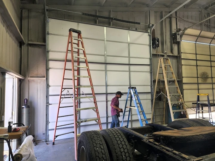 Technician repairing a large overhead door.