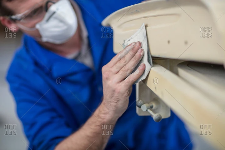 Technician sanding a garage door panel.