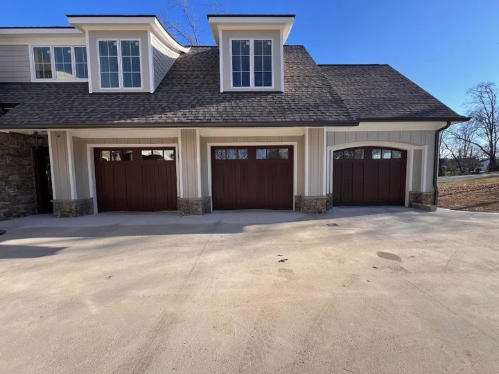 Three dark brown wooden garage doors on a house.