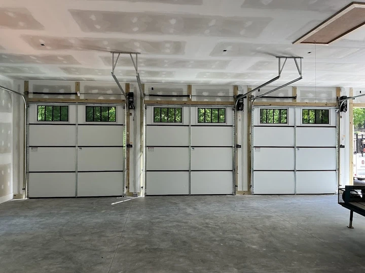 Three new garage doors installed in a garage.