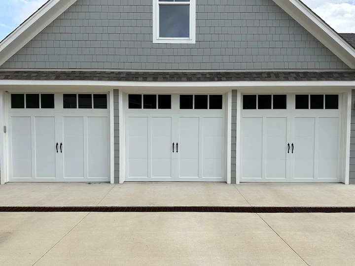 Three white carriage-style garage doors.