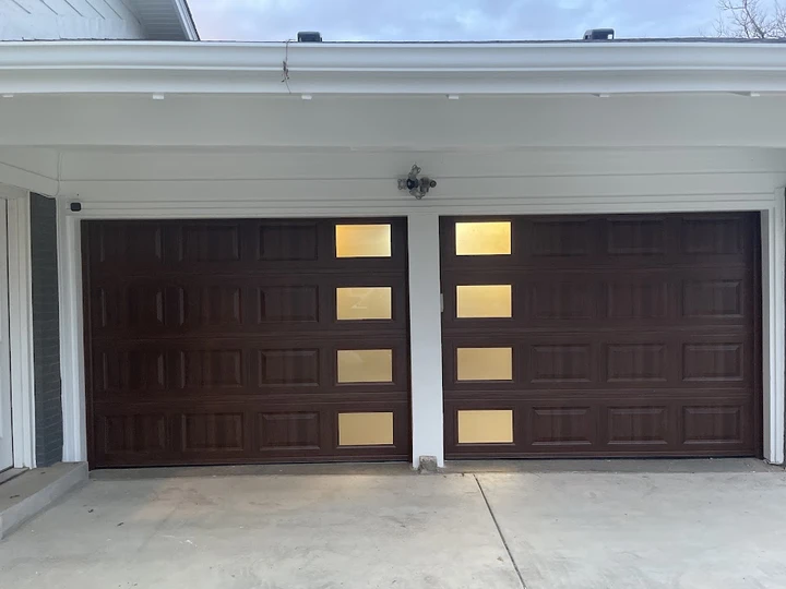 Two brown wooden garage doors with four windows each.