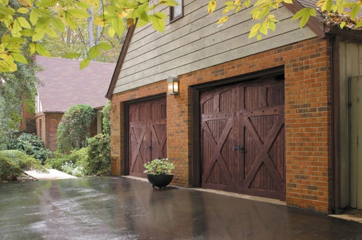 Wood carriage-style garage doors on brick home.