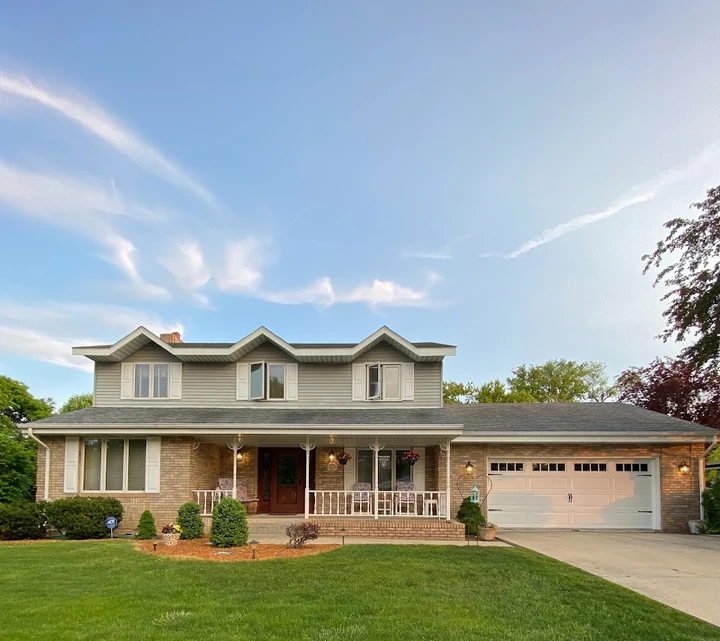 A tan brick house with a white garage door.
