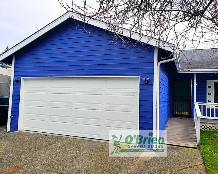 Blue garage exterior with a white door by O'Brien.