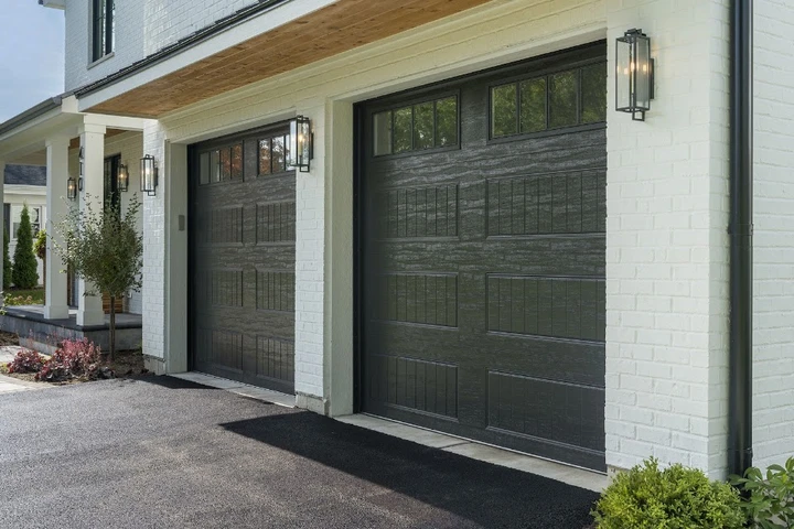 Modern black garage doors on a white brick home.