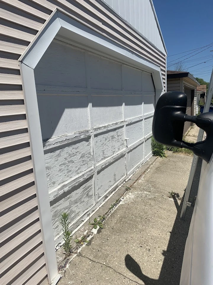 Old, peeling white garage door needing professional repair.