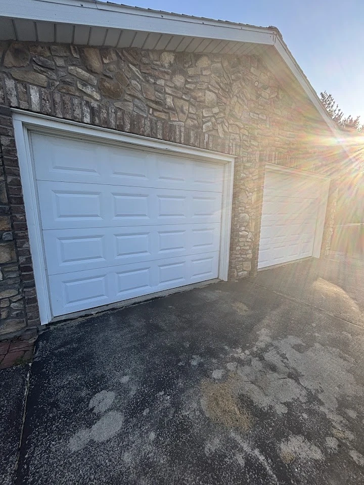 Residential garage doors at a stone-front home.